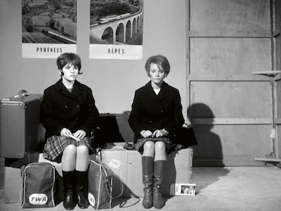 Two young women sitting on suitcases.