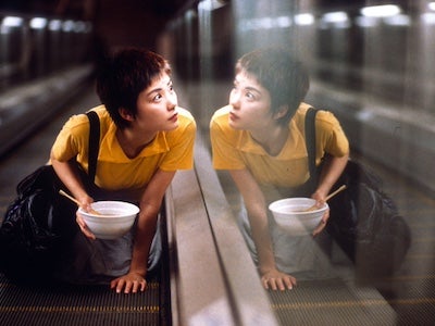 A woman looking through a window while holding a bowl.