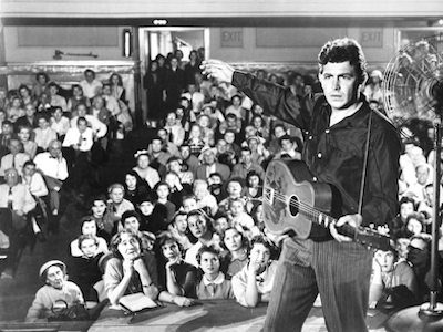 A man playing guitar in front of an audience.
