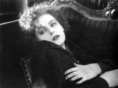 Greta Garbo looking weary on a sofa.