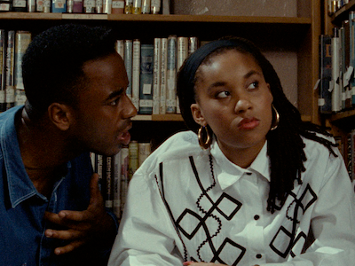 A woman looking away from a man who is talking to her in a library.
