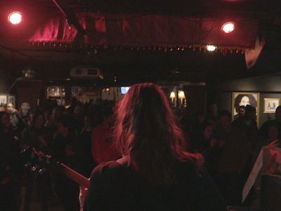 A person holding a guitar in front of an audience.
