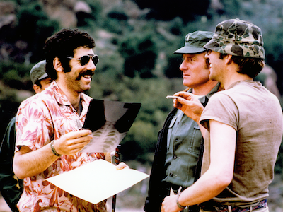 A man holding up an x-ray to two people in army attire.