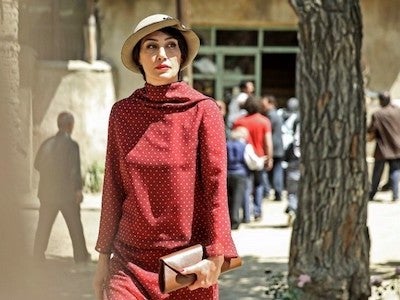 A woman in a hat walking in a village.