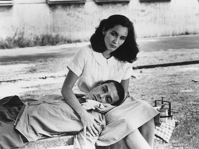 A man laying his head on a woman's lap on a bench.