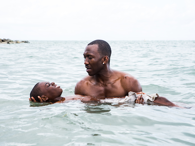 A man holding a young boy afloat in the ocean.