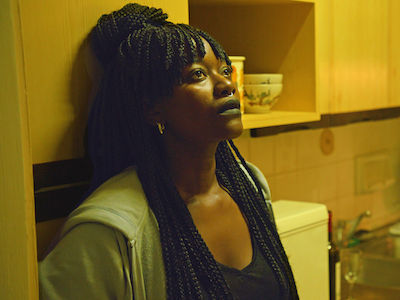 A woman leaning against a cabinet in a kitchen.