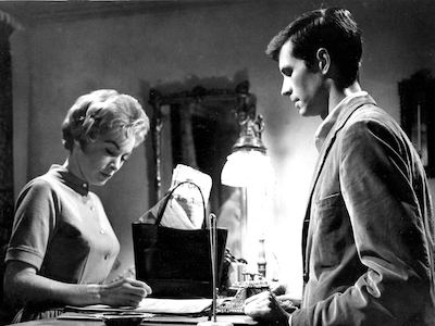 A woman signing in at a motel desk staffed by a man.