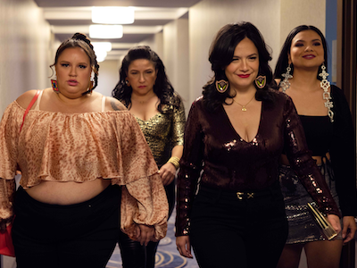 Four women walking down a hotel hallway.