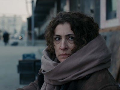 A woman wearing a large scarf and standing outside.