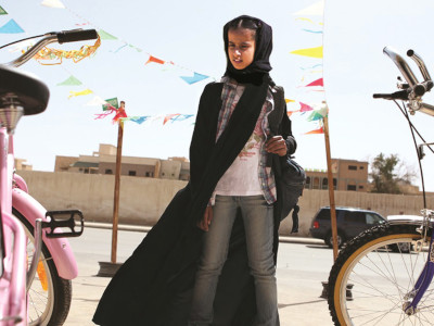 A young girl with a backpack next to bicycles.