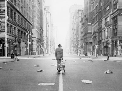 A man pulling a cart through an empty city.