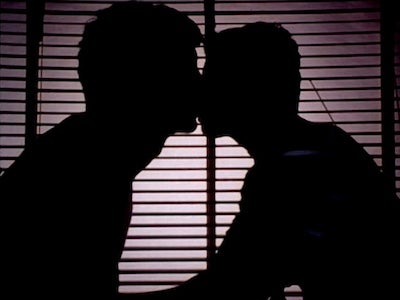 The silhouette of two men kissing.
