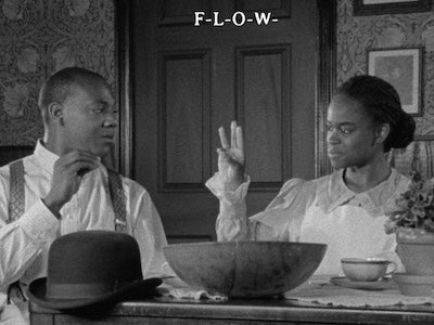 A woman spelling flowers through sign language to a man.