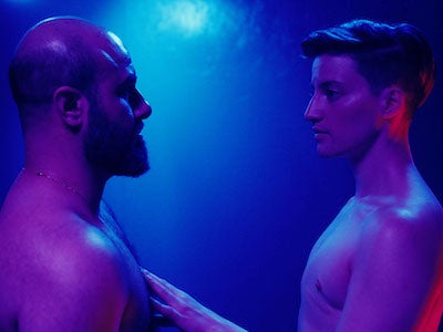 Two shirtless men looking directly at each other.