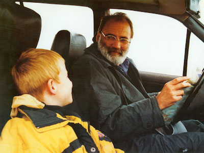 A man and a boy smiling in a car.