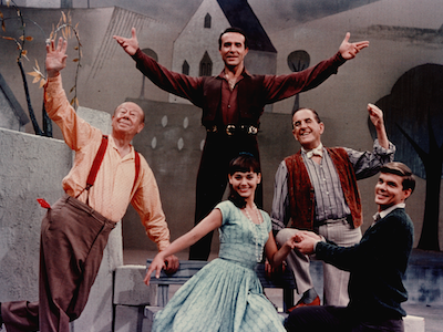 Five actors posing on a theater stage.