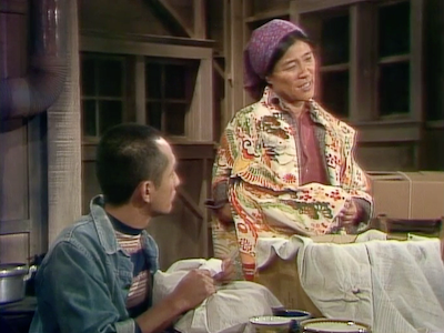 A Japanese American woman cloaked in a kimono as she packs her belongings with a family member.