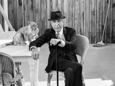 Leonard Cohen seated next to a cat.