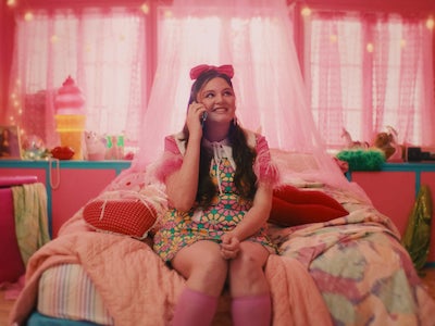 A person smiling on a bed and holding a phone.