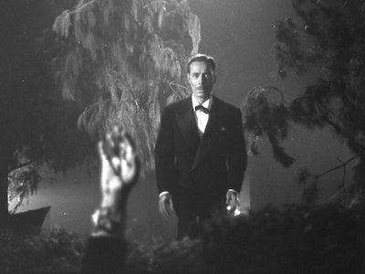 A man frightened by a hand that is emerging from the ground.