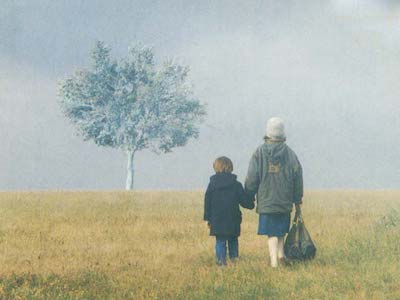 A woman and child holding hands in a field.