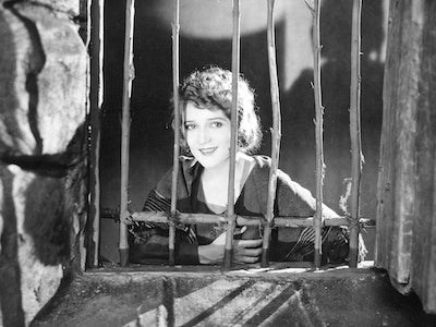 Mary Pickford smiling behind a window.