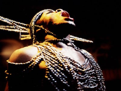 A person singing in a beaded outfit.