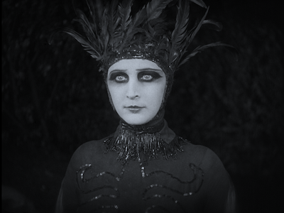 A person in a feathered costume and dramatic eye makeup.