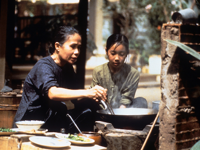 A young girl watching an older woman cook.