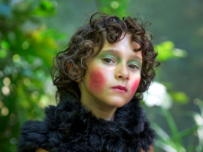 A young girl wearing exaggerated makeup and a furry scarf.
