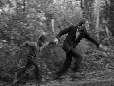 A boy and man holding hands and running among trees.