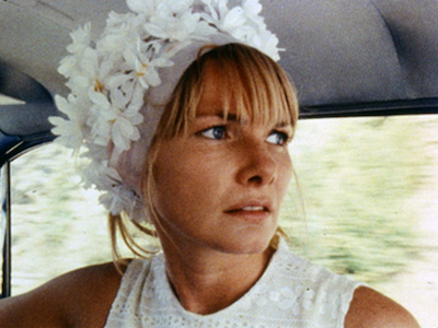 A woman wearing a flowery hat in a car.