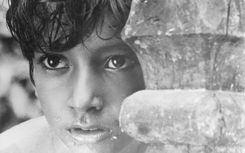 A young boy looking out from behind a wall.
