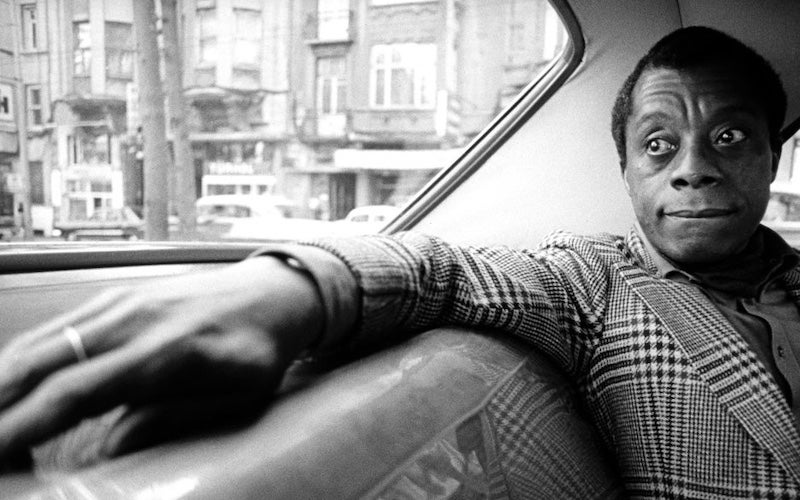 James Baldwin sitting in the back seat of a car.