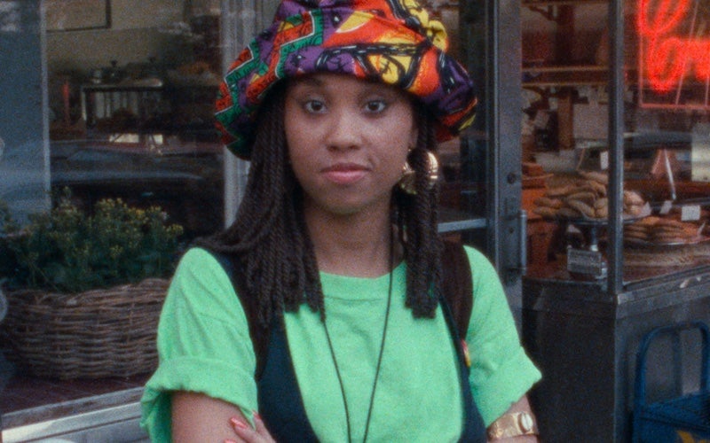 A young woman standing on a sidewalk with her arms crossed.