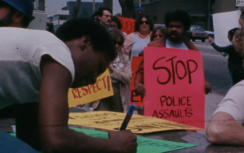 Demonstrators creating and holding signs against police assault.