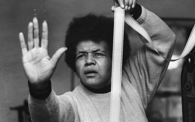 Sarah Maldoror holding up a palm and a strip of film.