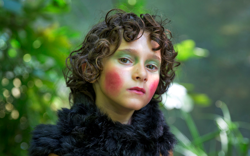 A girl with exaggerated makeup and a feather boa.