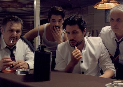 A group of men smoking and gathered around a radio.