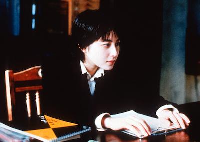 A woman sitting at a table with notebooks.