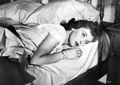 Ida Lupino lying in a bed.