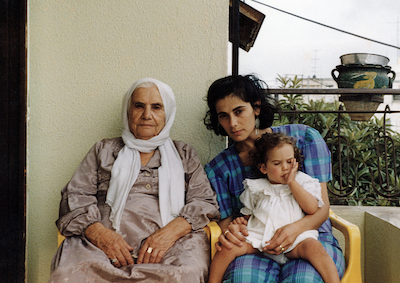 Two women and a baby sitting on a balcony.