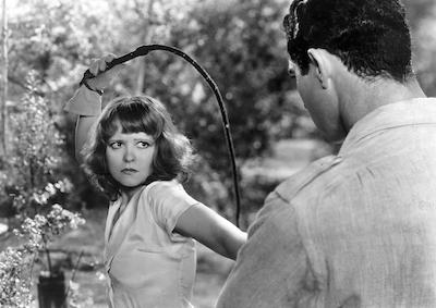 Actor Clara Bow holding a whip and glaring at a man.