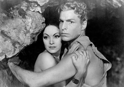 Actors Priscilla Lawson and Buster Crabbe with their arms wrapped around each other in a cave..