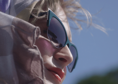 Closeup of a person wearing sunglasses and head scarf.