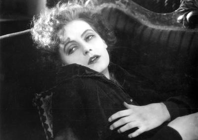 Greta Garbo looking weary on a sofa.