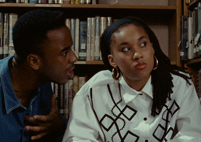 A woman looking away from a man who is talking to her in a library.