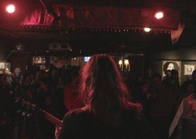 A person holding a guitar in front of an audience.