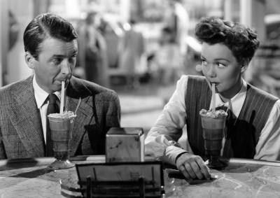 Actors James Steward and Jane Wyman drinking through straws at a counter.